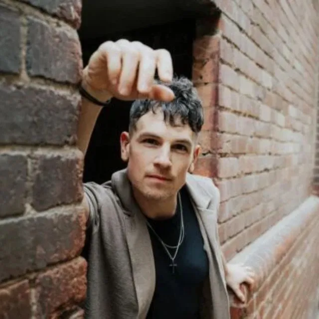 Michael Paynter - man leaning on a brick wall to promote his performance at Burnie Arts Centre on Saturday 11 July 2026 as part of Festival of Voices